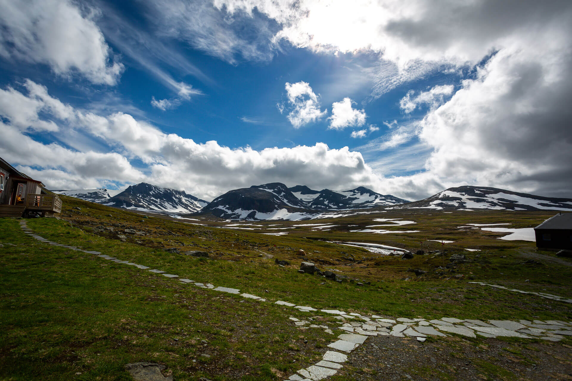 Vårbild över nordisk fjällvärld med snöfläckar på bergen